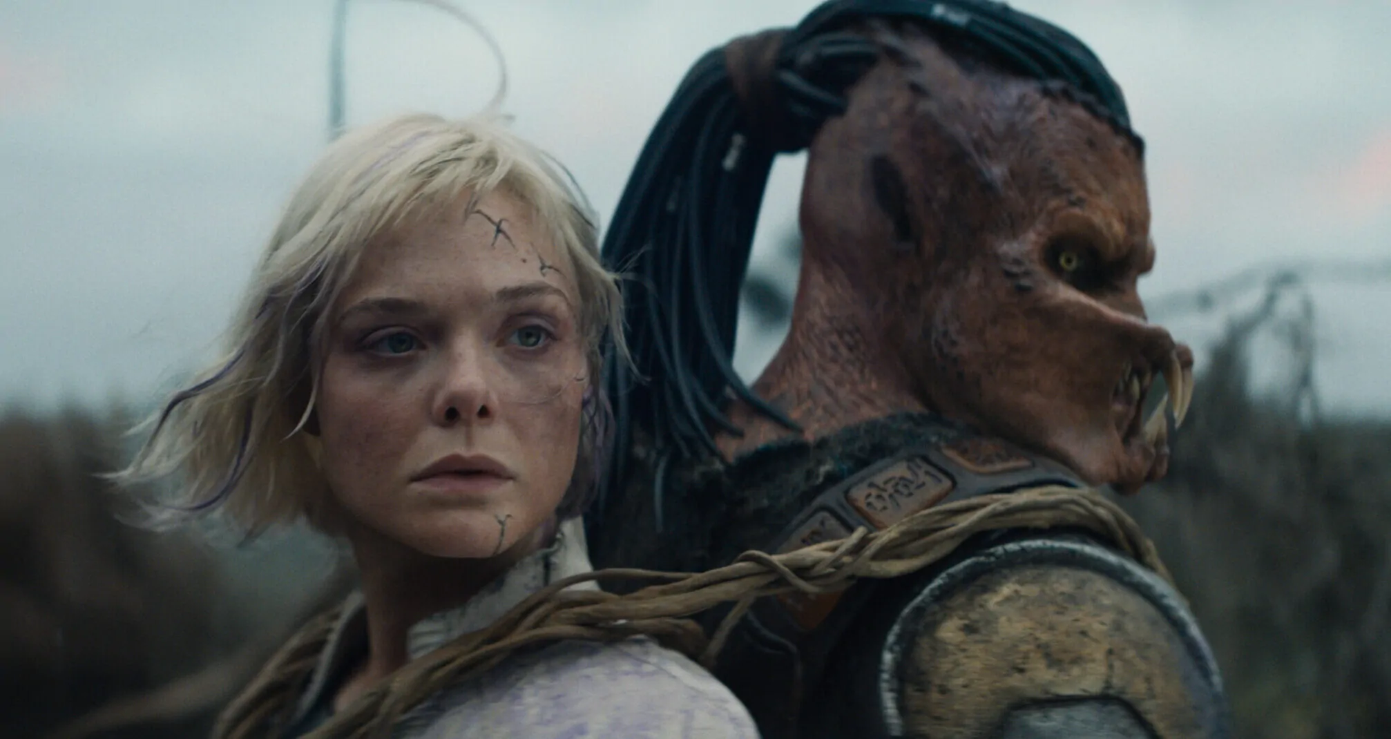 (L-R) Thia (Elle Fanning) and Dek (Dimitrius Schuster-Koloamatangi) in 20th Century Studios' PREDATOR: BADLANDS film. Photo courtesy of 20th Century Studios. © 2025 20th Century Studios. All Rights Reserved.